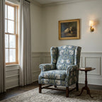 Wingback chair upholstered in William Morris Pimpernel Blue and Sage in a panelled room with a brass sconce