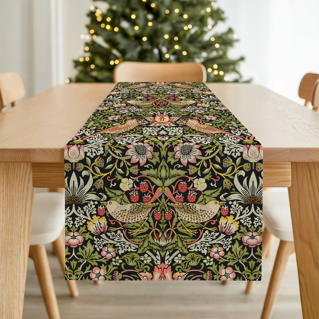 William Morris Strawberry Thief table runner with floral and bird pattern on a wooden table in front of a Christmas tree.