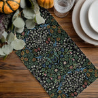 Decorative Halloween table runner with William Morris Blackthorn floral pattern on a wooden table with pumpkins and glasses.