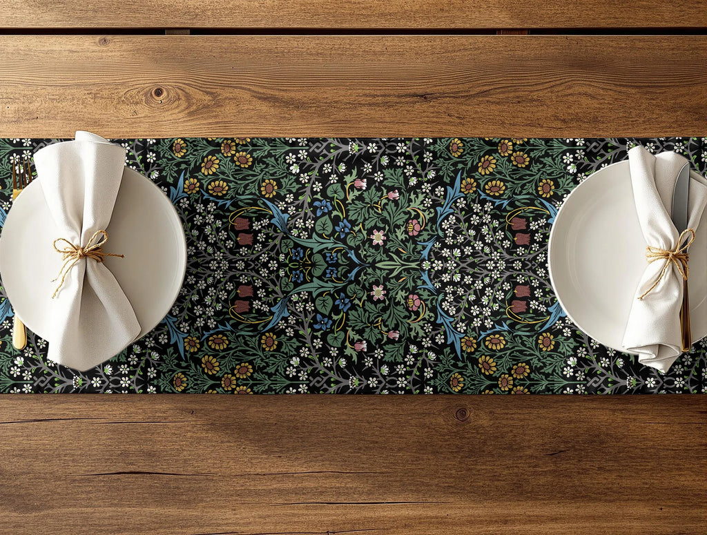 Two plates with folded napkins on a floral William Morris table runner over a wooden table.