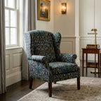 A wingback armchair upholstered in William Morris Blackthorn fabric in Classic Black.
