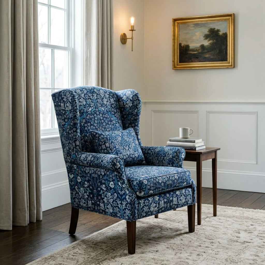 A wingback armchair upholstered in William Morris Blackthorn fabric in English Lapis.
