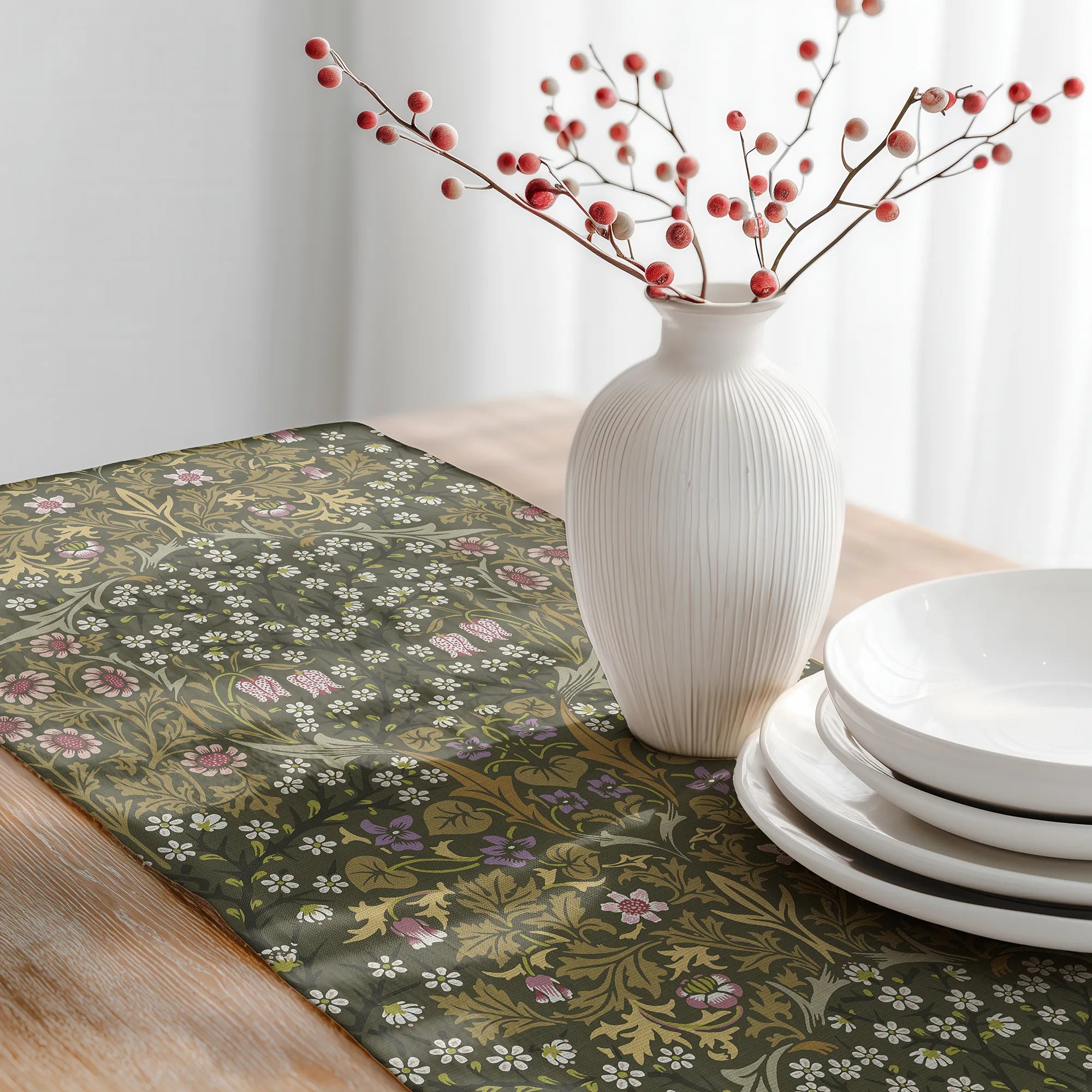 Decorative table setting with a William Morris table runner in olive green, white vase with red berries, and white plates.