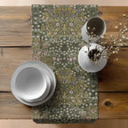 Decorative Easter table setting with a floral-patterned William Morris table runner in olive green on a wooden table.