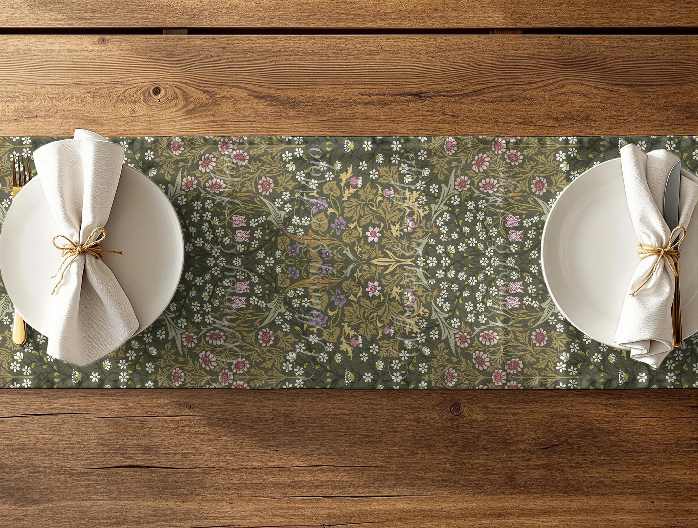 Floral patterned table runner - William Morris Blackthorn in olive green - with white plates and napkins on a wooden table.