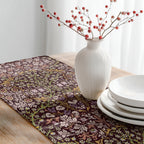 Table setting with a floral-patterned William Morris table runner in Maroon burgundy, white vase with red berries, and white plates.