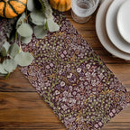 William Morris table ranner in maroon burgundy, floral table runner on a wooden table with pumpkins and glasses.