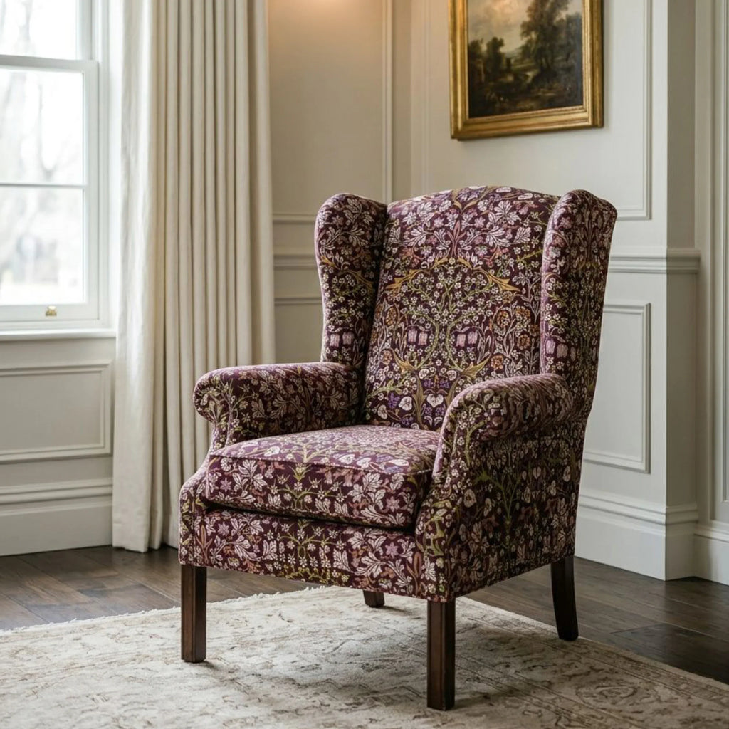 A wingback armchair upholstered in William Morris Blackthorn fabric in Maroon & Mauve.