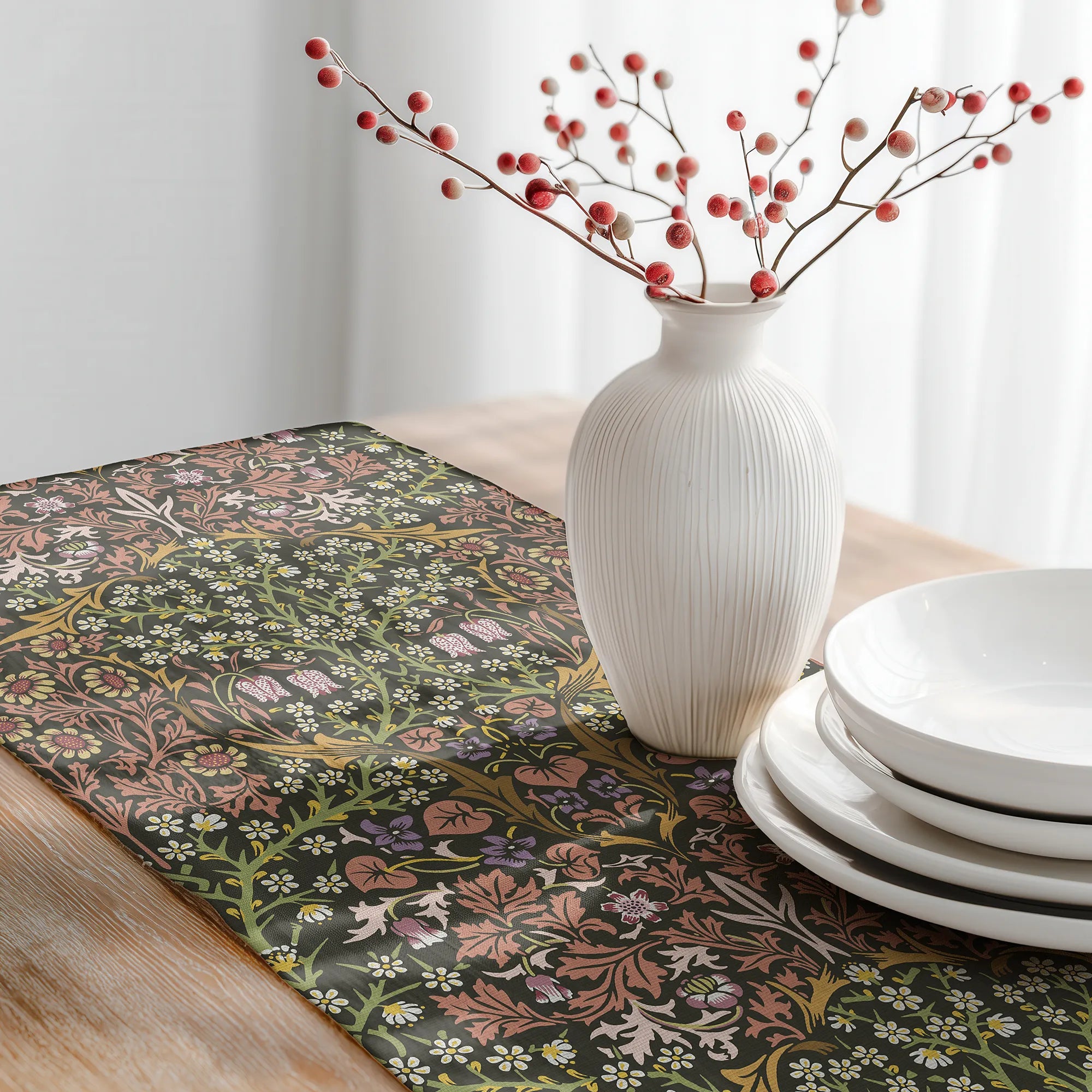 Decorative table setting with a William Morris table runner in Secret Garden colorway, white vase with red berries, and white plates.