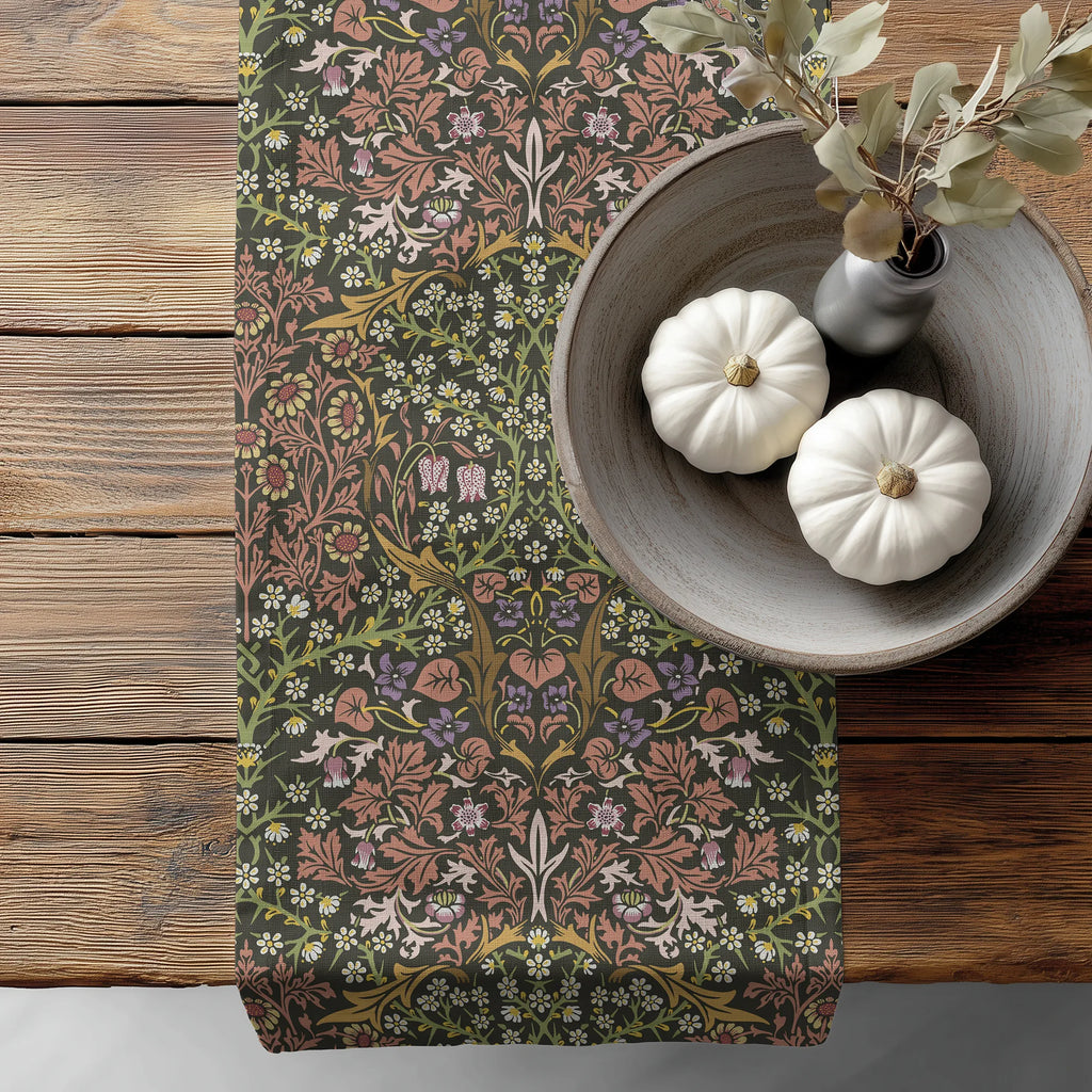 William Morris Blackthorn table runner in Earthy Garden, with floral pattern, on a wooden surface with pumpkins and a vase.