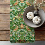 William Morris Strawberry Thief table runner styled on a wooden dining table with bowl centerpiece, showcasing the historic Arts and Crafts botanical pattern.