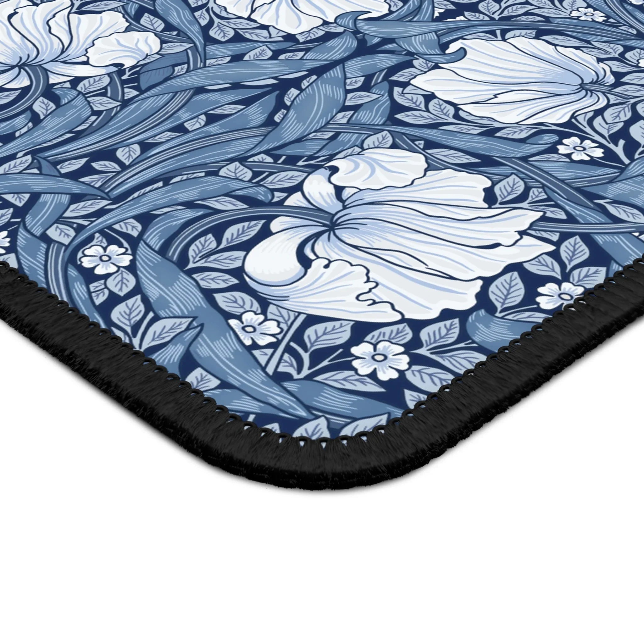 Corner close-up of the William Morris Pimpernel desk mat in Elegant Blue, showing the printed surface and stitched edge.