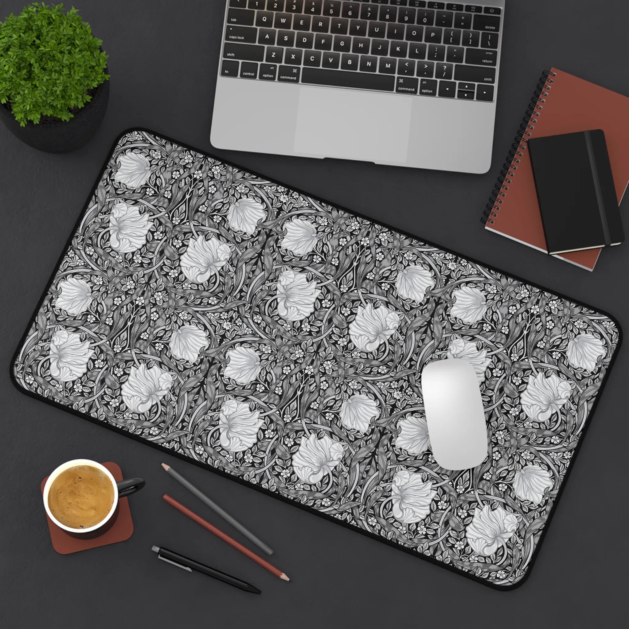 Floral patterned William Morris Pimpernel desk mat on a desk with laptop, coffee, and stationery items.