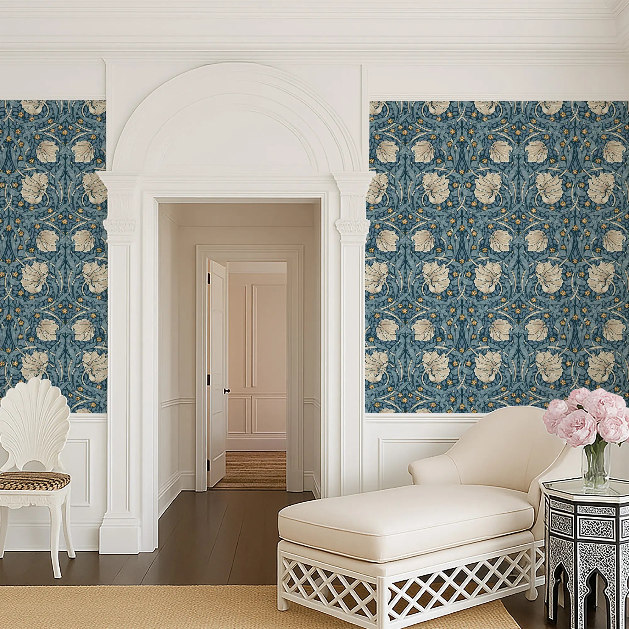Living room with decorative William Morris wallpaper in blue tones, white chair, and floral arrangement.