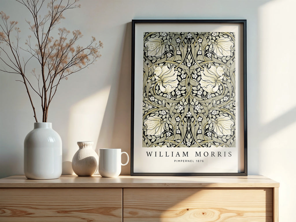 William Morris Pimpernel poster in sage and black, shown framed in a black frame and displayed on top of a cabinet