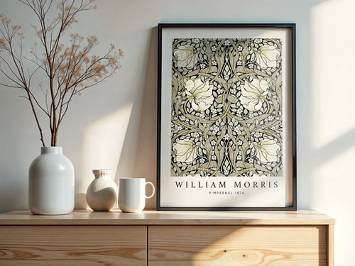William Morris Pimpernel poster in sage and black, shown framed in a black frame and displayed on top of a cabinet