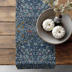 William Morris table runner with floral pattern on a wooden surface with pumpkins and a vase. Blackthorn table linens in Dusky Blue garden