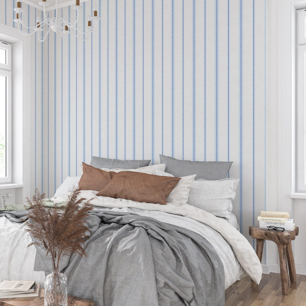 Neutral stripe wallpaper in Chalk and French Blue tones behind a bed, creating a calm French country bedroom with cottagecore and heritage-inspired decor.