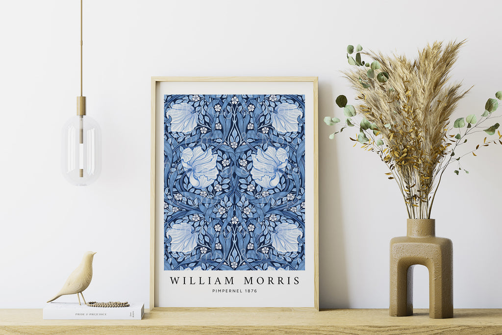 Framed William Morris Pimpernel print in blue, displayed on a wooden surface with a vase of dried plants