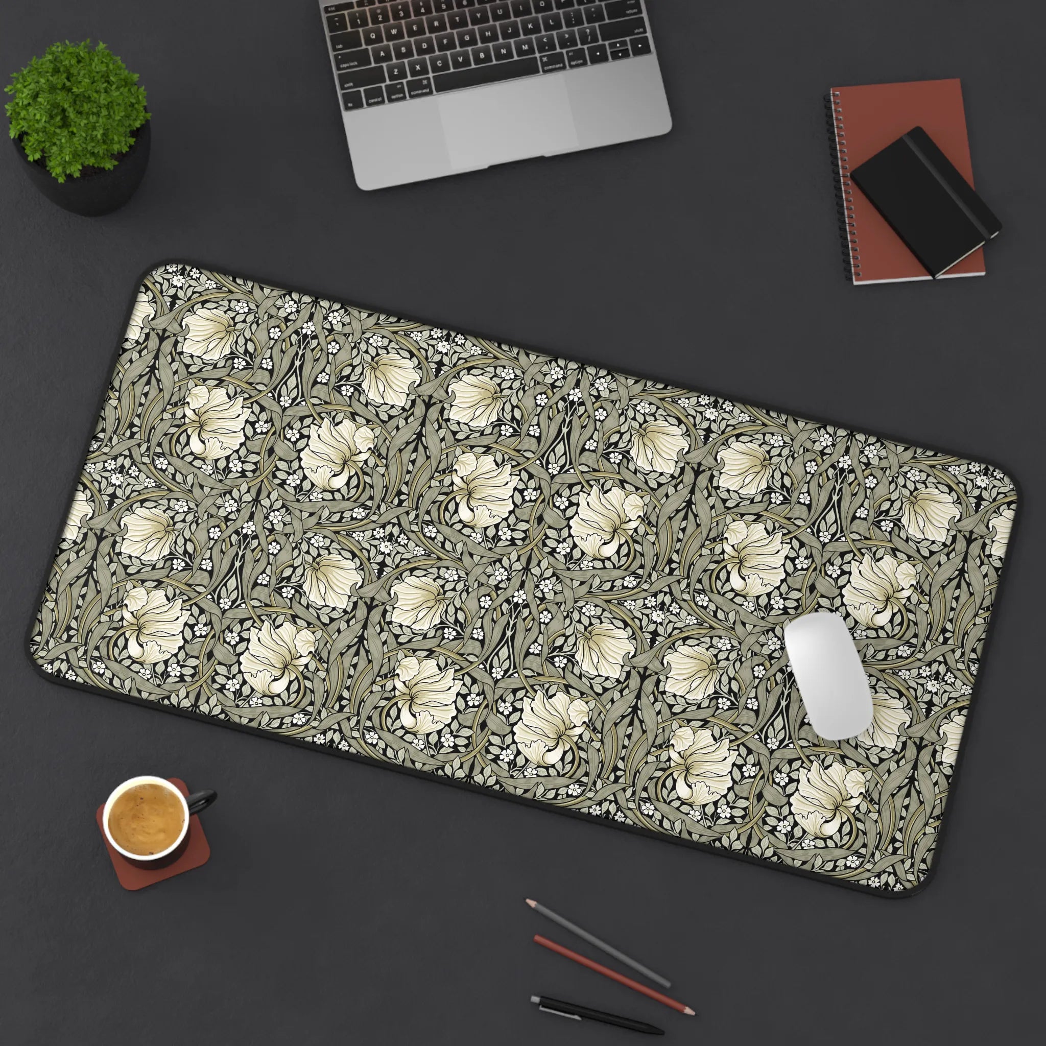 Floral patterned William Morris desk pad on a dark surface with office items.