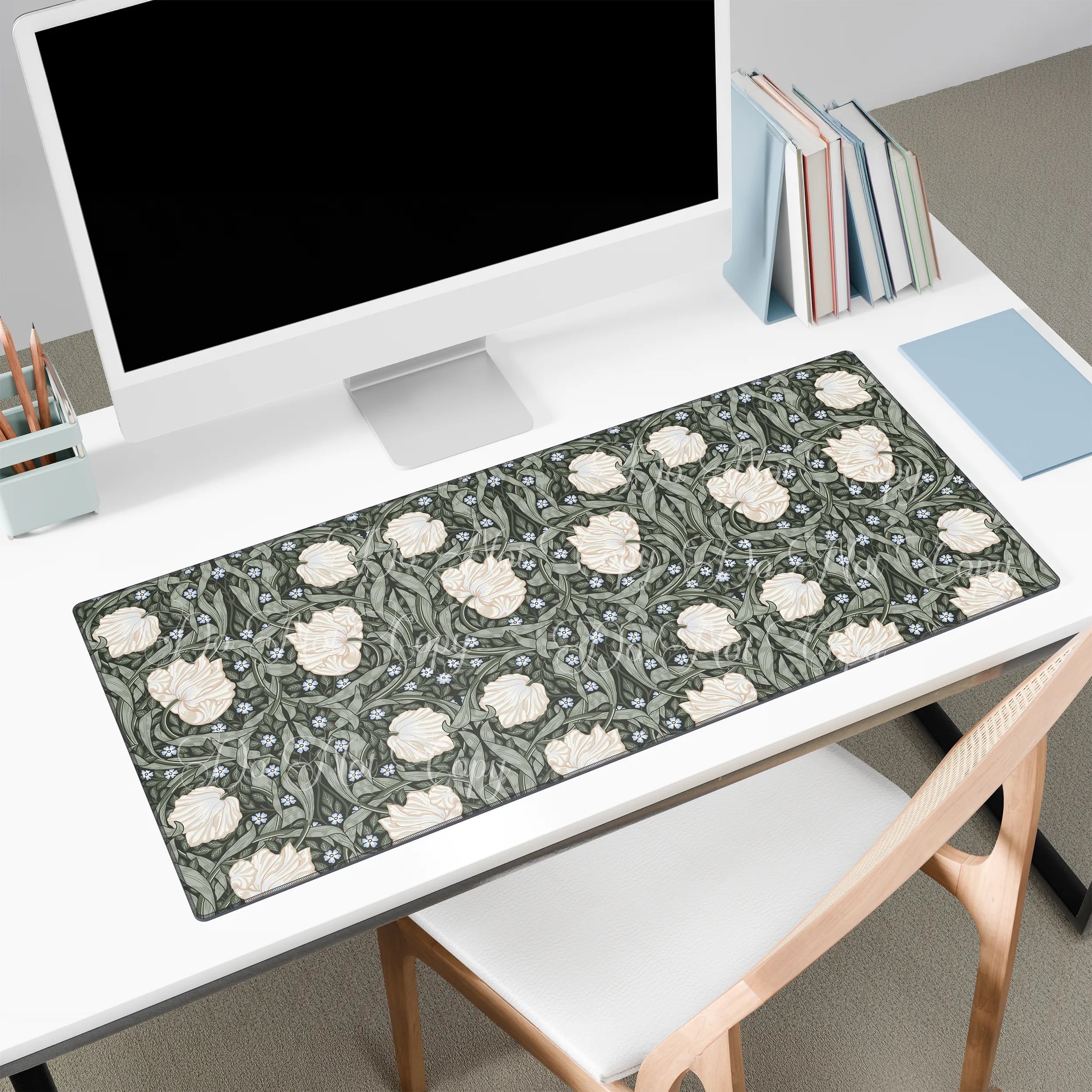 Large floral William Morris desk mat on a white desk with a computer monitor and books.