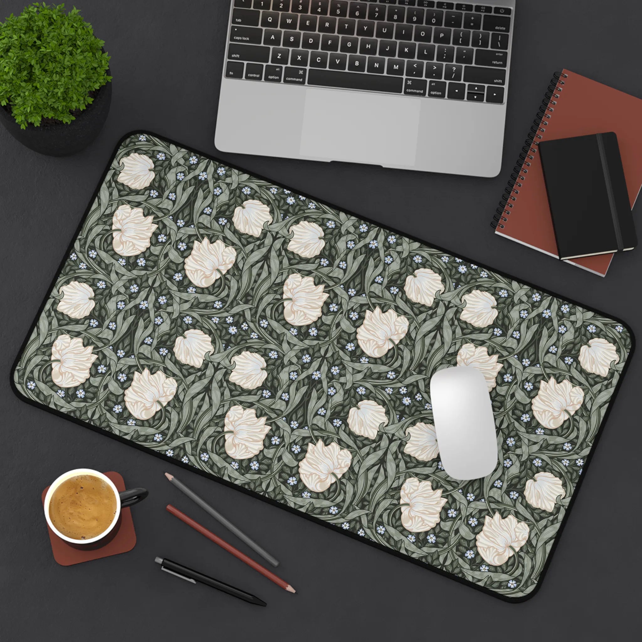 Floral patterned William Morris desk mat mouse pad on a desk with laptop, coffee, and stationery items.