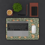A laptop computer is on top of a William Morris Pimpernel desk mat featuring the iconic Pimpernel pattern in sage green and copper