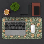 A laptop computer is on top of a William Morris Pimpernel desk mat featuring the iconic Pimpernel pattern in sage green and copper