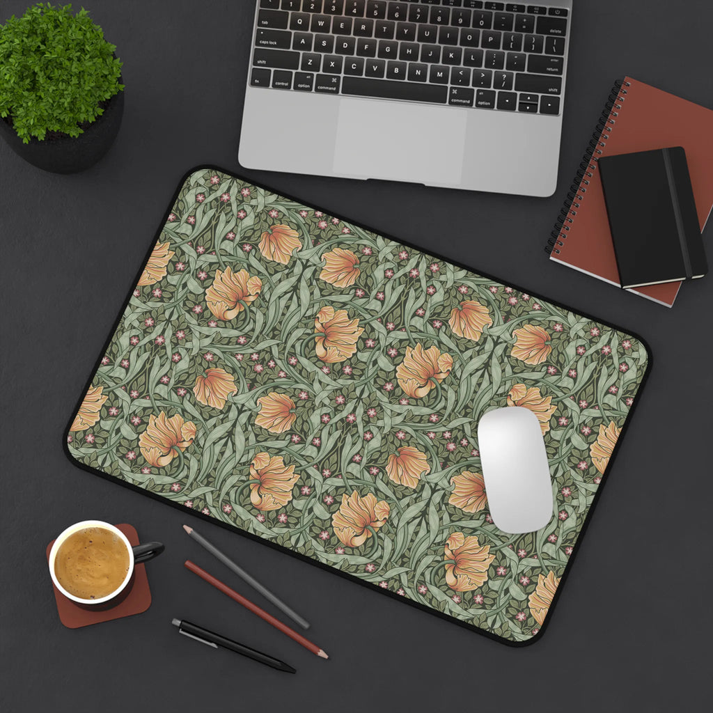 A flatlay scene of a William Morris desk pad featuring the iconic Pimpernel pattern in sage green and copper, with a laptop computer, a cup of coffee, notebooks and a plant