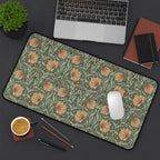 A flatlay scene of a William Morris desk mat featuring the iconic Pimpernel pattern in sage green and copper, with a laptop computer, a cup of coffee, notebooks and a plant