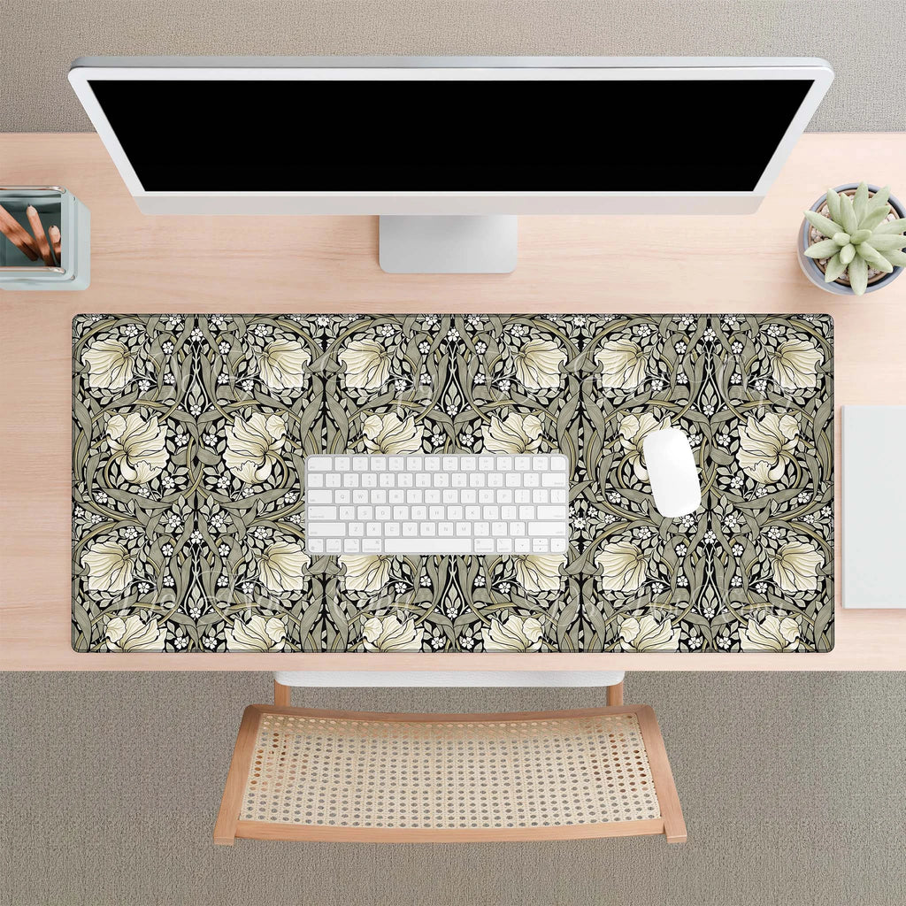 Desk setup with a floral patterned William Morris desk mat, keyboard, and computer monitor.