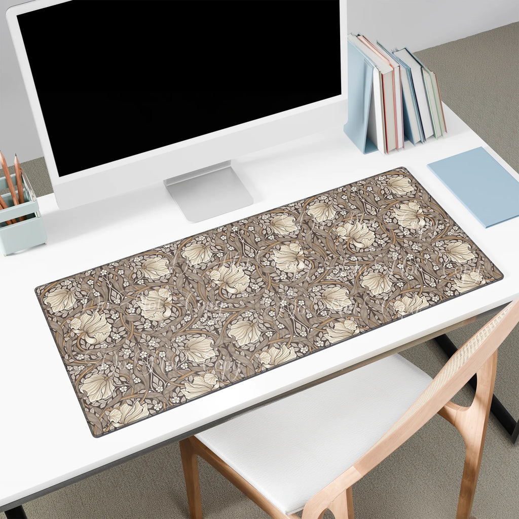 Desk setup with a large floral William Morris desk mat pad, computer monitor, and books.