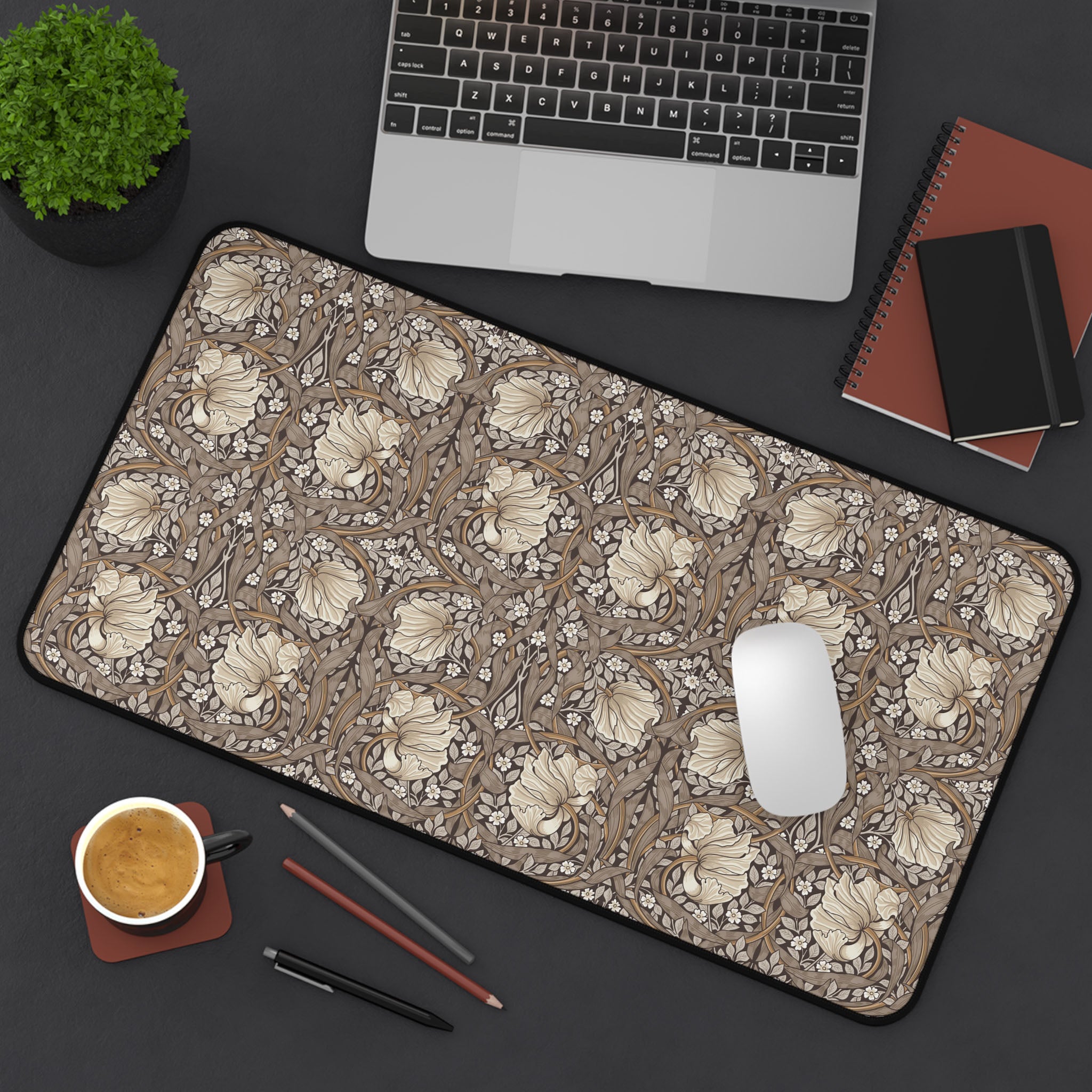 Floral patterned William Morris desk mat mouse pad on a desk with laptop, notebook, and coffee cup.