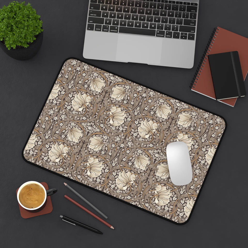 William Morris Pimpernel desk mat in rich cocoa brown and beige, with a mouse, laptop, coffee, and stationery on a dark surface.