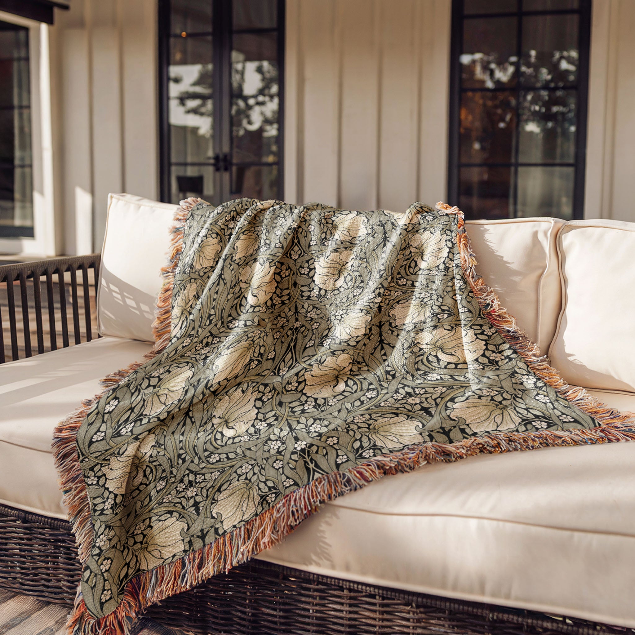 William Morris Pimpernel woven throw blanket draped over sofa, vintage botanical pattern in sage and cream on black
