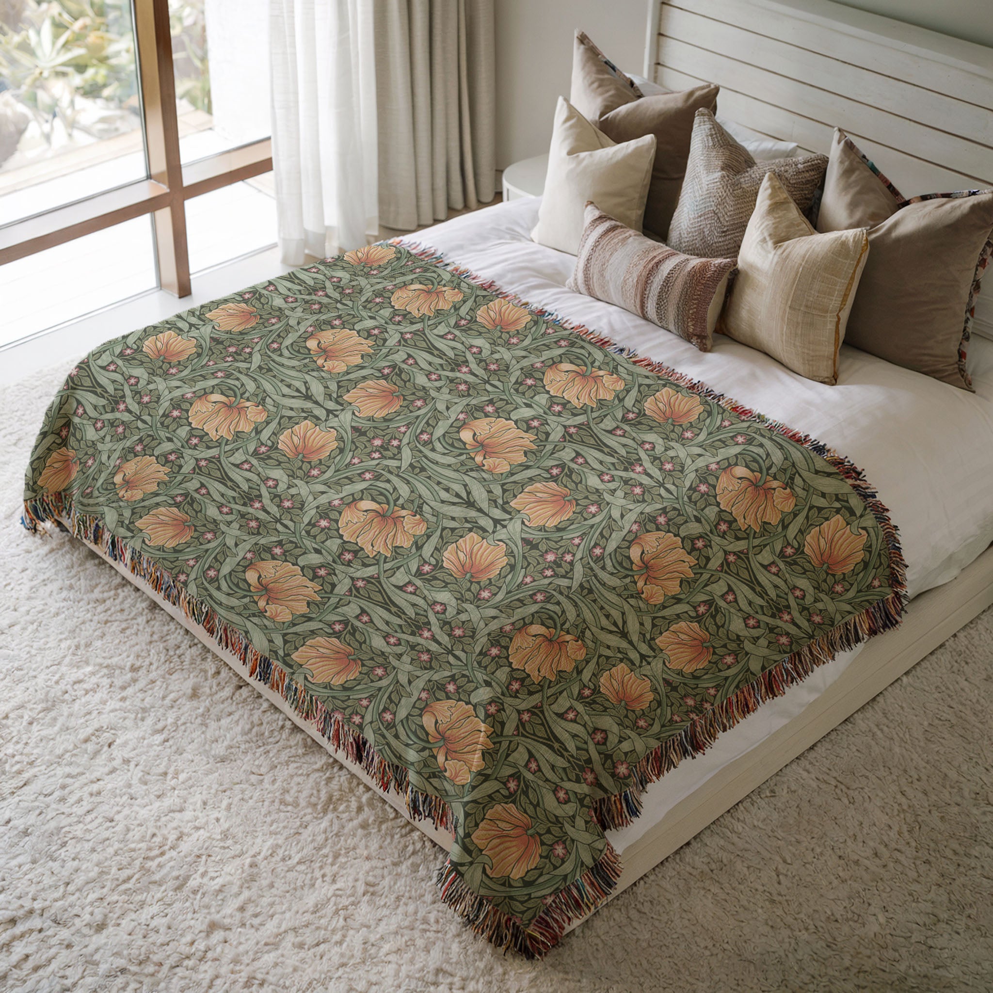 William Morris Pimpernel woven blanket styled on bed. Soft botanical throw in sage green and copper tones adding texture to cozy bedroom decor