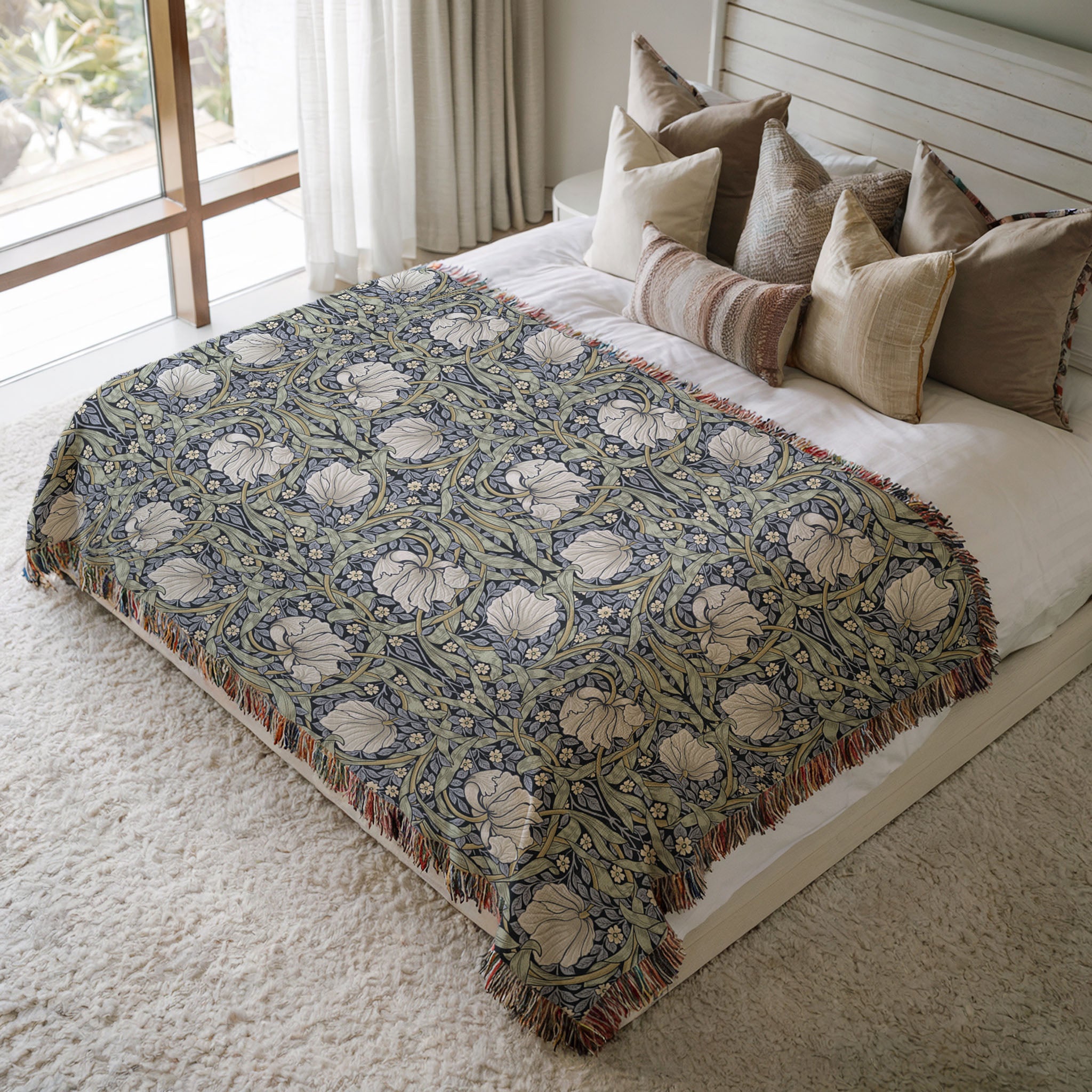 William Morris Pimpernel woven blanket styled on bed. Soft botanical throw in blue and sage green tones adding texture to cozy bedroom decor