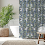 Bathroom with a William Morris Pimpernel  shower curtain in blue and sage, white bathtub, and wooden stool.
