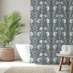 Bathroom with a William Morris shower curtain in Blue and Gold Pimpernel, white bathtub, and decorative elements.